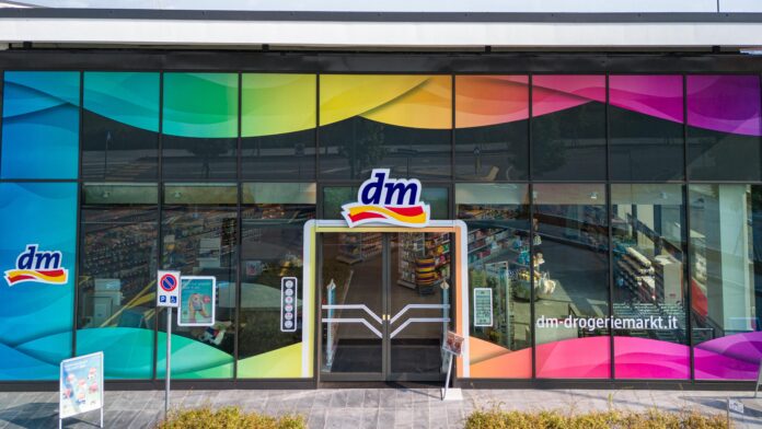 Facade of a dm-drogerie markt with rainbow-tinted glass panels and central entrance door.