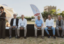 Outdoor panel discussion with six people seated on a black stage; a woman on the left speaks into a microphone, Granoro banner in the background.