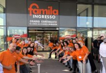 GMF inaugura il nuovo Famila di Calcinaia e annuncia altri investimenti in Toscana Staff in orange shirts line up at the Famila entrance for a ribbon-cutting ceremony outside the store as onlookers watch the opening.