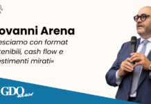 Giovanni Arena: «Cresciamo con format sostenibili, cash flow e investimenti mirati» Giovanni Arena speaks into a microphone on a promotional banner with Gruppo Arena logo and a blue diagonal strip showing PR Italia Edizioni and GDQ News logos.