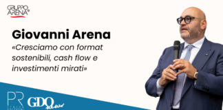 Giovanni Arena: «Cresciamo con format sostenibili, cash flow e investimenti mirati» Giovanni Arena speaks into a microphone on a promotional banner with Gruppo Arena logo and a blue diagonal strip showing PR Italia Edizioni and GDQ News logos.
