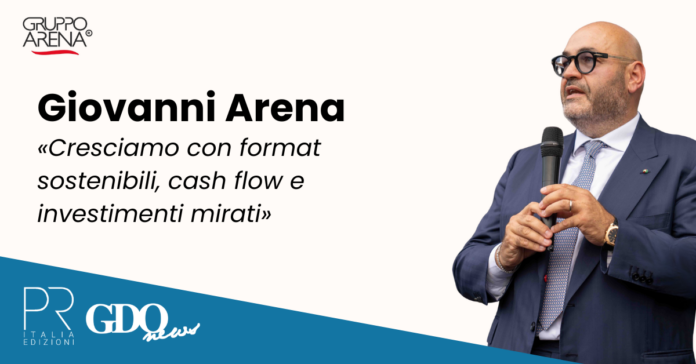 intervista-giovanni-arena (1) Giovanni Arena speaks into a microphone on a promotional banner with Gruppo Arena logo and a blue diagonal strip showing PR Italia Edizioni and GDQ News logos.