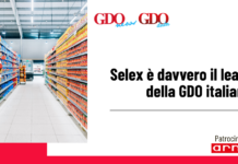 Selex è davvero il leader della GDO italiana? Photo of a supermarket aisle filled with colorful products on both sides, plus a white panel with the headline: "Selex è davvero il leader della GDO italiana?" Patrocinato da arneg on the bottom right.