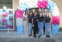 Cesar raggiunge quota 900 negozi con il nuovo Acqua & Sapone di Elmas Nine staff members in navy shirts pose under a colorful balloon arch at the store entrance, smiling for a group photo.