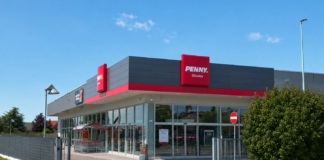 Penny Ghislba supermarket exterior with red signage and glass entrance under a clear blue sky.