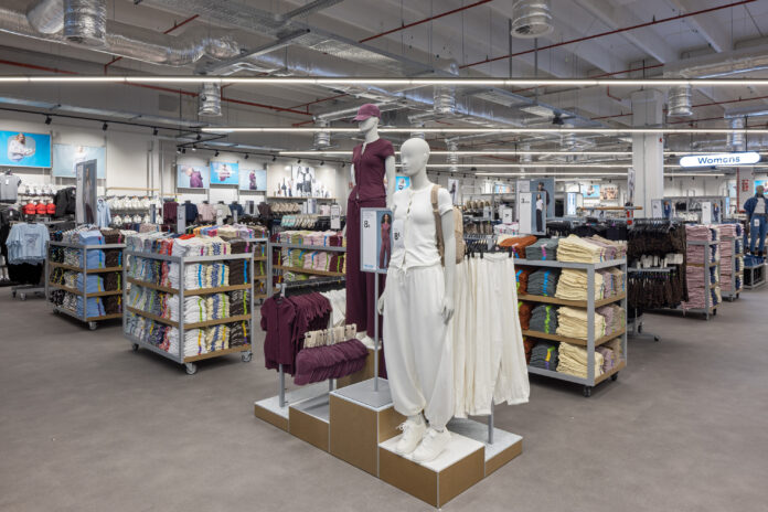 Parma_Primark store Store interior with mannequins wearing maroon and white outfits in the center, surrounded by shelves of folded clothes and a 'Womens' sign in the background.