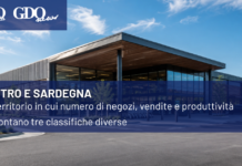 Centro e Sardegna, un territorio in cui numero di negozi, vendite e produttivitĂ raccontano tre classifiche diverse Modern commercial building with a blue overlay banner: title 'CENTRO E SARDEGNA' and subtitle about shops, sales and productivity; branding logos top-left and sponsor logo bottom-right.
