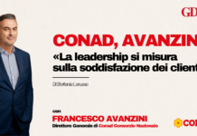 Conad, Avanzini: «La leadership si misura sulla soddisfazione dei clienti» Man in a navy suit on a beige background left of a bold Italian headline about leadership and customer satisfaction, with Conad and GDO News logos on the right.