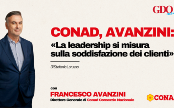 Conad, Avanzini: «La leadership si misura sulla soddisfazione dei clienti» Man in a navy suit on a beige background left of a bold Italian headline about leadership and customer satisfaction, with Conad and GDO News logos on the right.