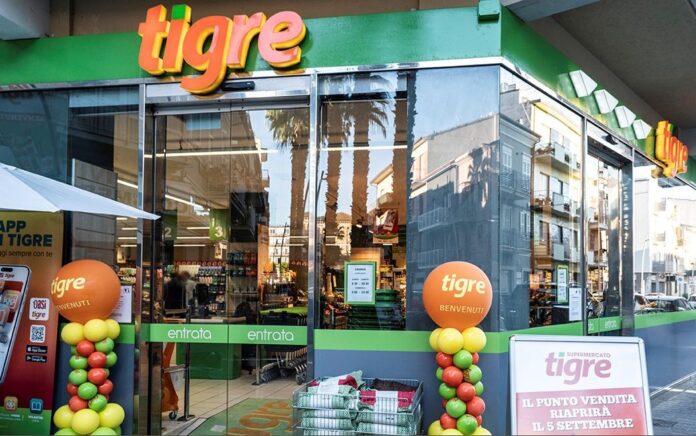 gabrielli tigre Front of a Tigre supermarket with glass doors, green trim, and orange logo balloons outside the entrance.