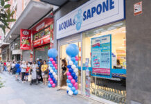Acqua & Sapone presidia la Spagna centrale con due nuovi punti vendita People line up outside a Cosmopolitan-style shopfront with blue and white balloons decorating the entrance and a large ACQUA& SAPONE sign above the doorway, on a busy street.
