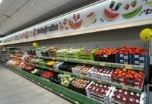 iN’S Mercato cresce in Lombardia con lo store di Villa Cortese Supermarket produce aisle with a colorful fruit banner reading 'Ortofrutta' and crates of tomatoes and other fruit below.
