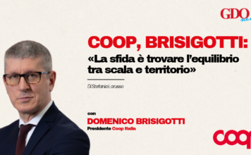 Coop, Brisigotti: «La sfida è trovare l’equilibrio tra scala e territorio» Domenico Brisigotti in a suit on the left with a beige background; bold red headline about Coop Brisigotti and balancing scale and territory, plus author credit and logos (GDO News top right, Coop bottom right).