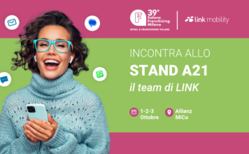 Promotional banner showing a smiling woman with teal glasses and sweater, inviting visitors to Stand A21 by LINK at Salone Franchising Milano.