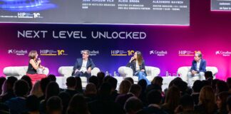 HIP Italia porta a Bologna il Pizza & Pasta Business Summit Panel discussion on stage with four speakers seated in white armchairs under a large 'NEXT LEVEL UNLOCKED' banner; audience visible in foreground.