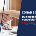 Selex e Conad: due modelli per conquistare l’Italia Handshake between two people on a business banner about CONAD and SELEX sponsorships.