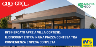 Modern supermarket exterior with a bold blue news banner across the front reading: "IN’S mercato apre a Villa Cortese: Il discount entra in una piazza contesa tra convenienza e spesa completa" and sponsor logos in the corners.