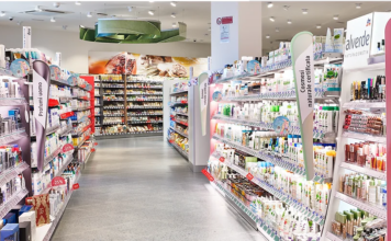Dm Italia inaugura un nuovo drugstore a Bassano del Grappa Wide, bright cosmetics aisle in a store with shelves stocked of skincare and beauty products on both sides.