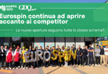 Eurospin continua ad aprire accanto ai competitor. Le nuove aperture seguono tutte lo stesso schema? Group of workers outside a building with a large green banner about Eurospin openings and gold EUROSPIN balloons in front.