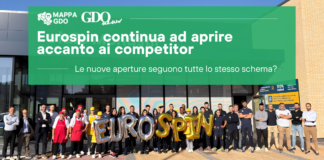 Group of workers outside a building with a large green banner about Eurospin openings and gold EUROSPIN balloons in front.