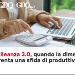 Coop Alleanza 3.0, quando la dimensione diventa una sfida di produttività Person typing on a laptop while using a calculator on a desk; logos 'Top Sales', 'GDO data', 'GDO news' appear in the top-left.