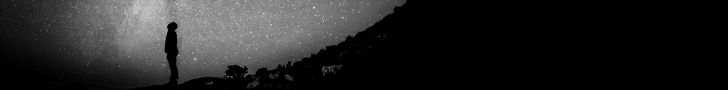 Silhouette of a person standing on a hill under a star-filled night sky, with darkness framing the foreground.”] ,